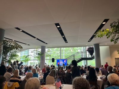 crowd in an atrium listen to two girls speaking