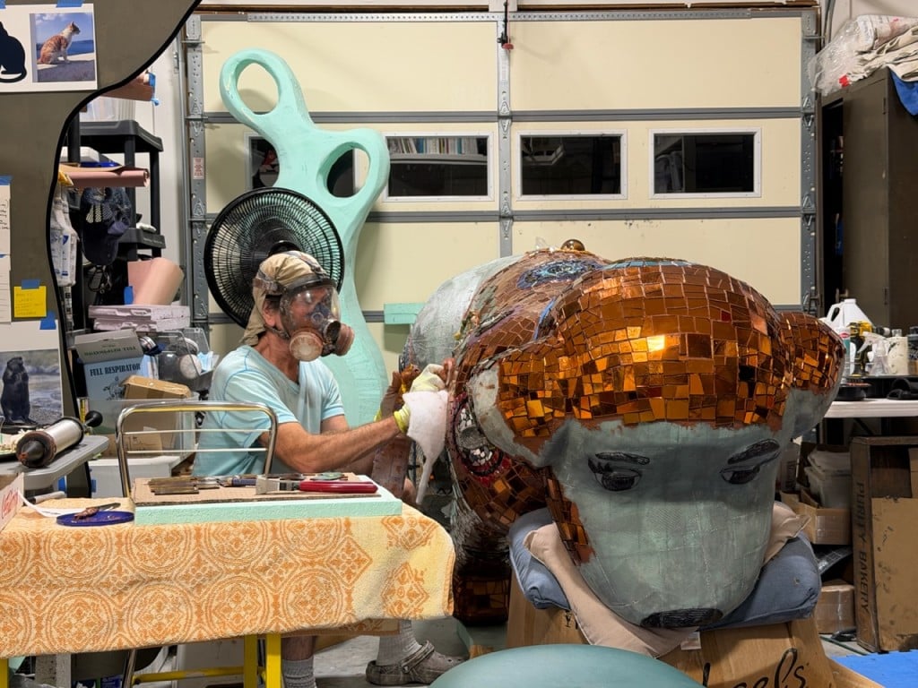 Artist Duffy Healey masks up to grout the mosaic work on Ginger the Positivity Watch Dog. Elizabeth Laul Healey photo