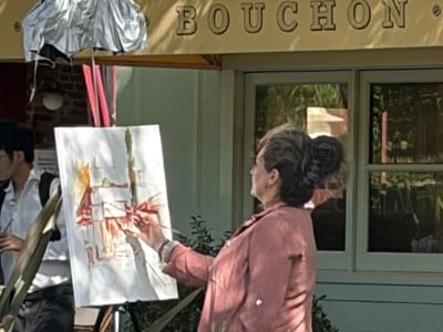 An artist paints live outside Bouchon and Bouchon Bakery this week.