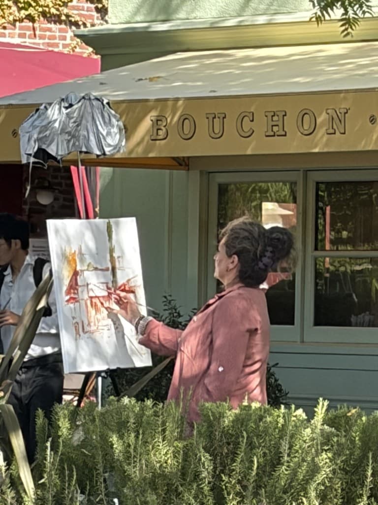 An artist paints live outside Bouchon and Bouchon Bakery this week.